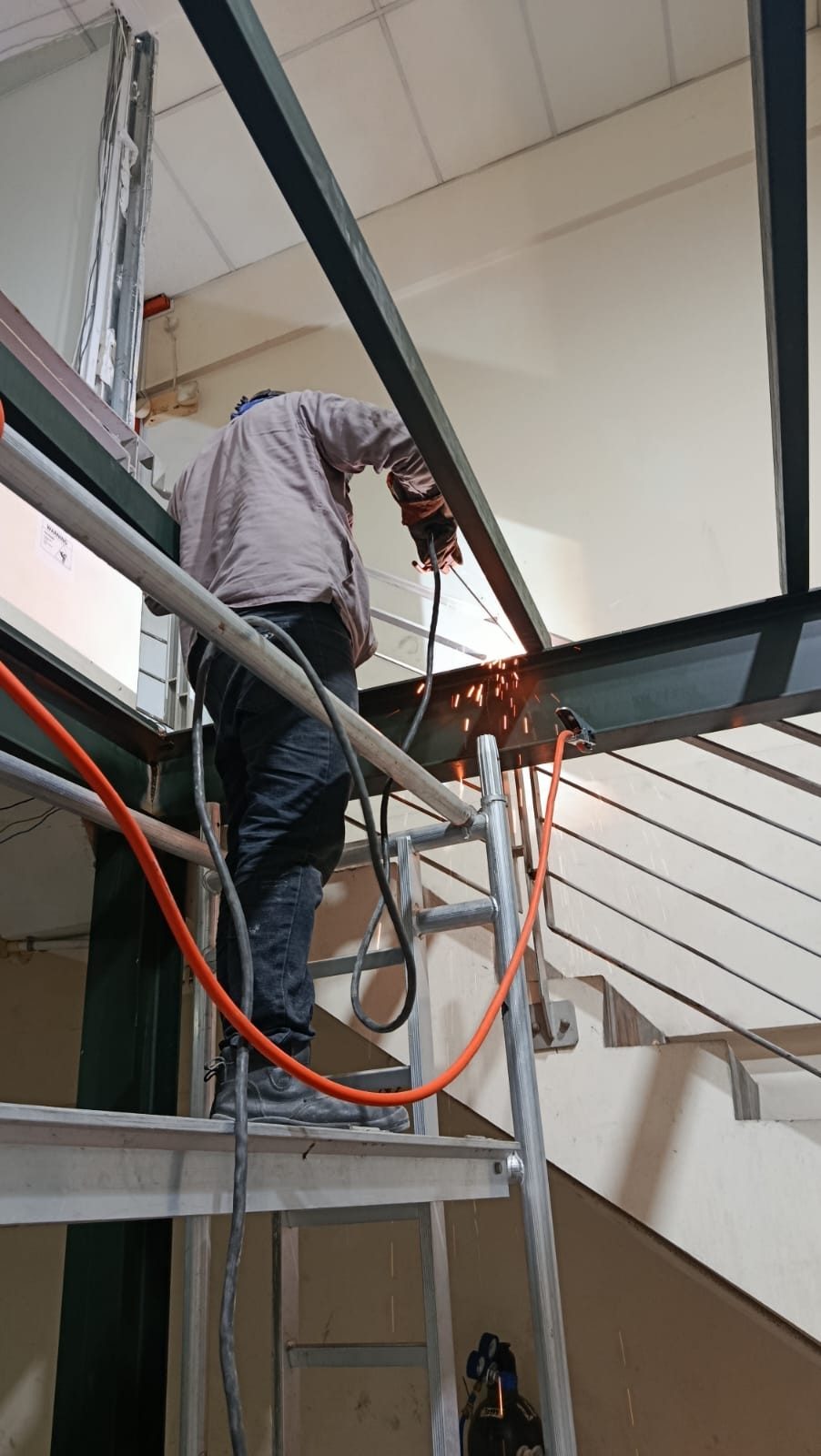 Worker on a ladder installing mezzanine steel members at Frontier Industrial Building