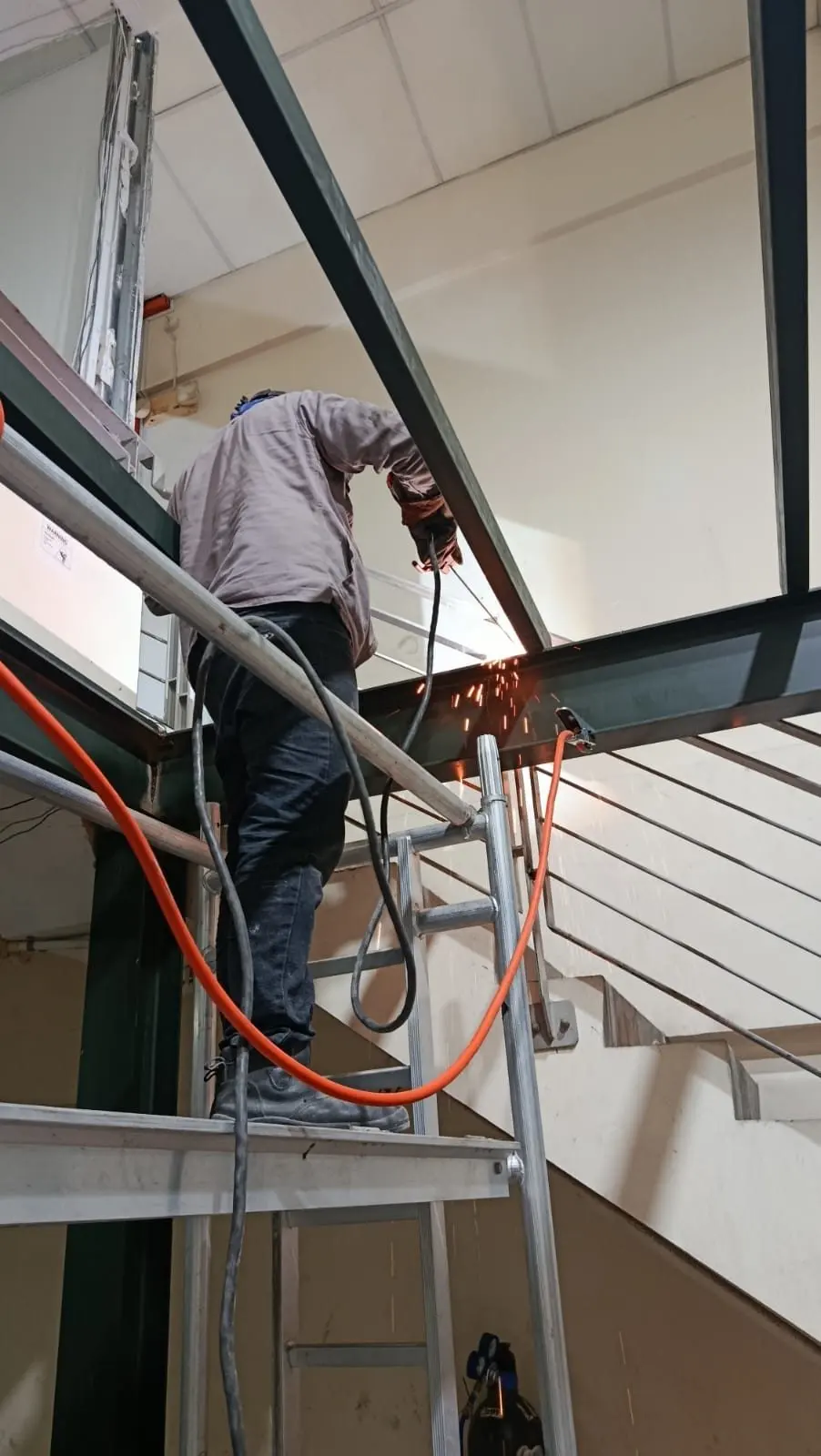 Worker on a ladder installing mezzanine steel members at Frontier Industrial Building