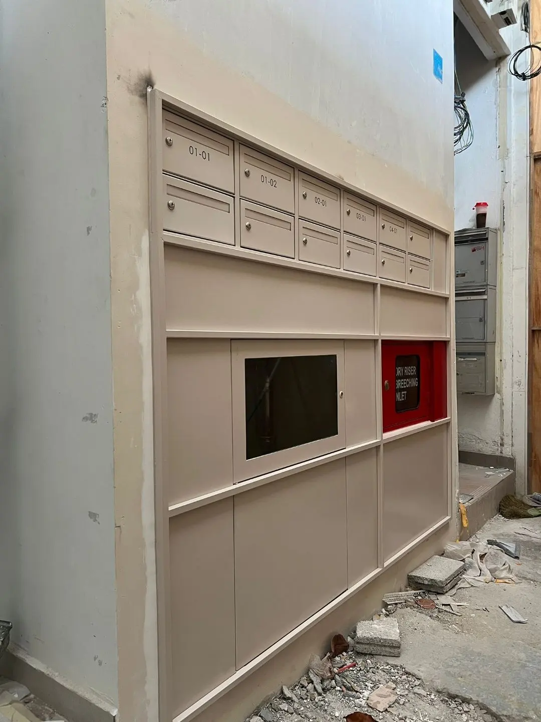 Completed SS304 mailbox bank installed against the residential wall at Jalan Penhas with rows of letter slots and locker doors