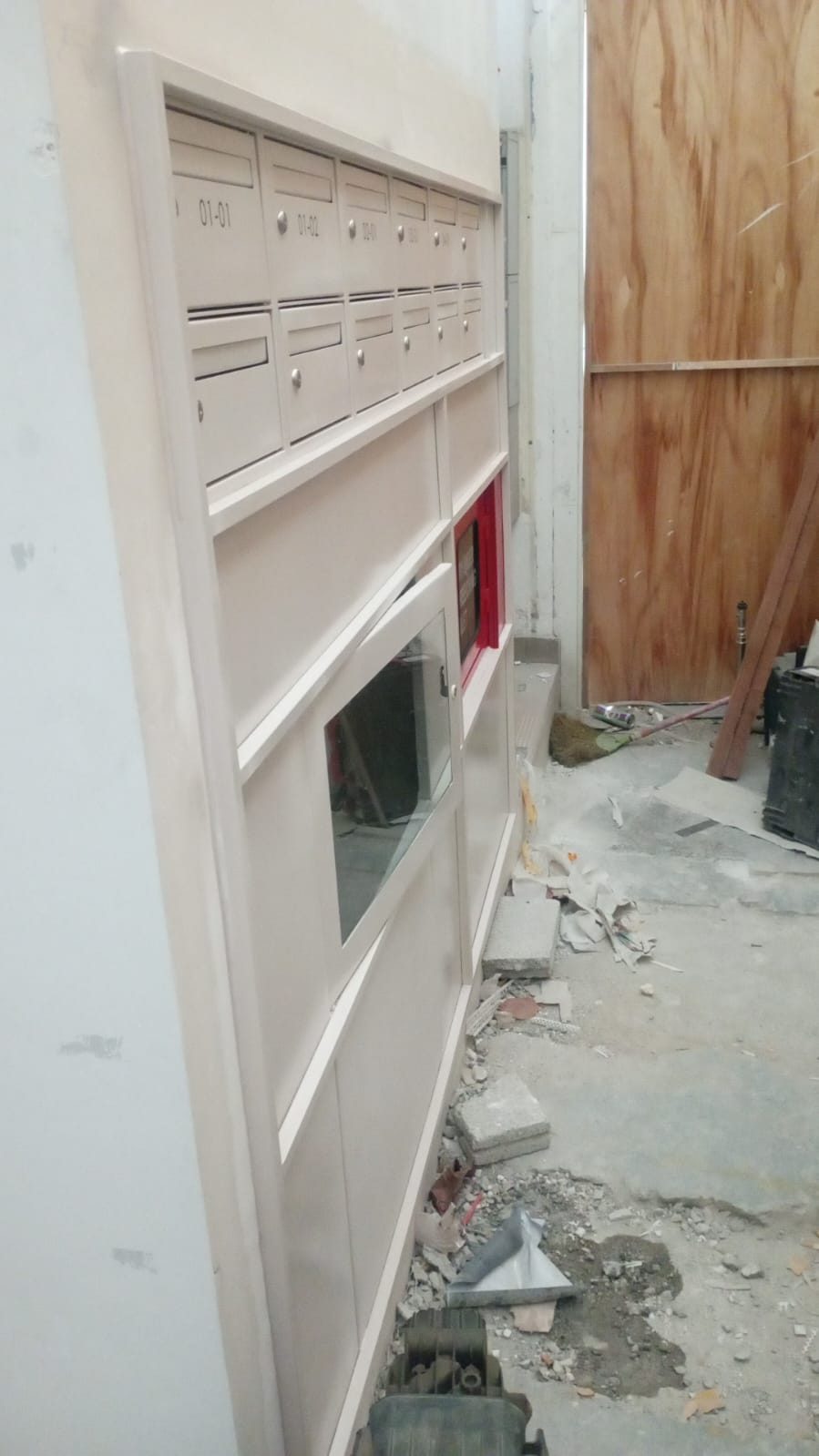 Side context view of the Jalan Penhas SS304 mailbox panel during installation with site materials in the foreground