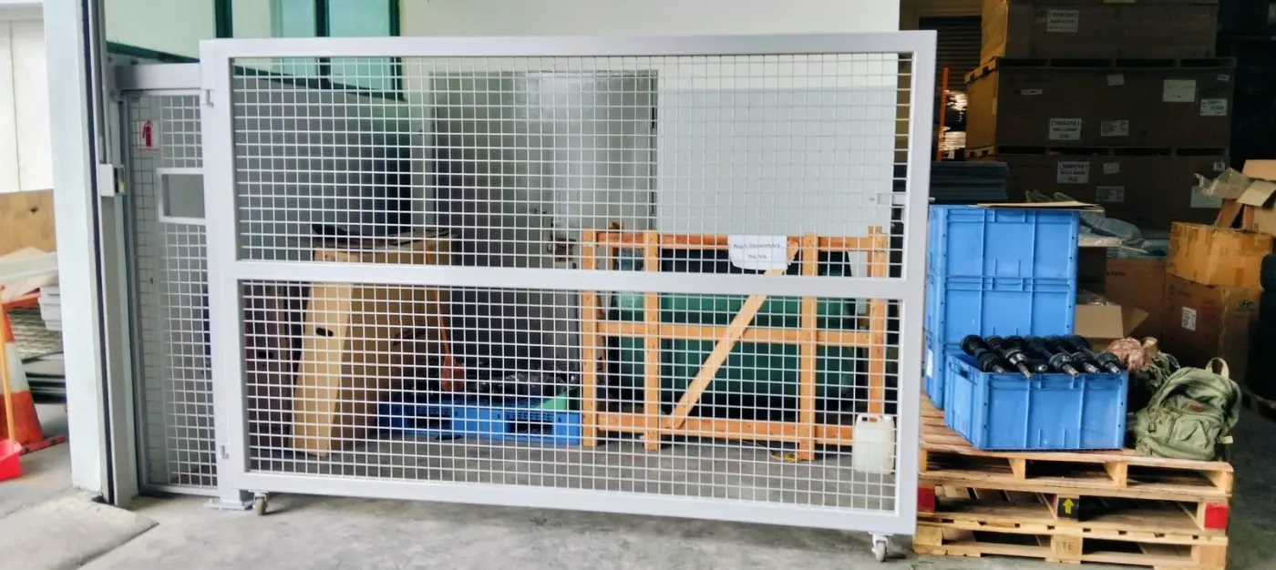 Side view of the full sliding mesh-panel metal gate at Strides Premier showing the steel frame and rolling track