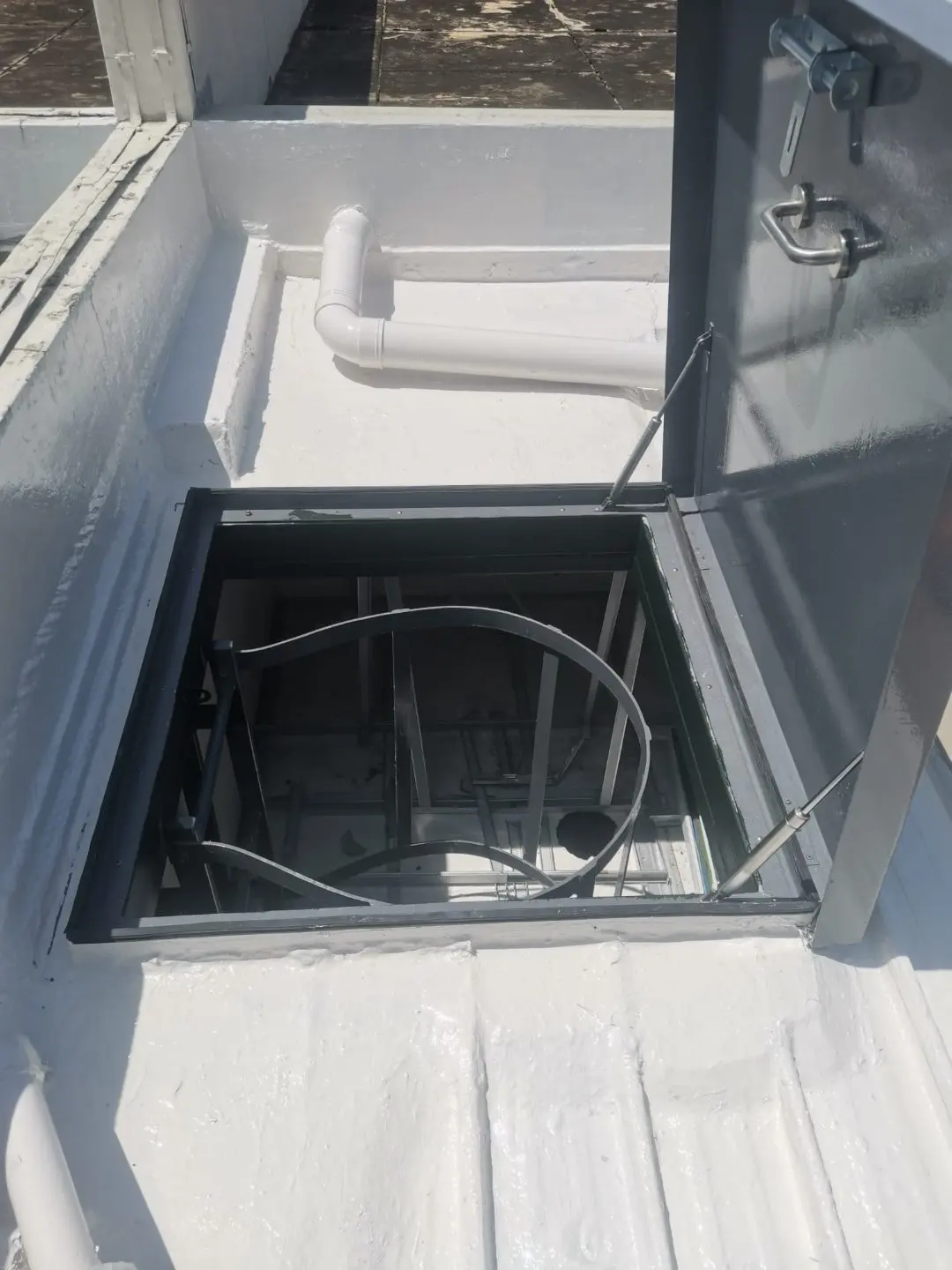 Open roof access hatch at Tuas View showing the ladder structure below and gas-strut stays
