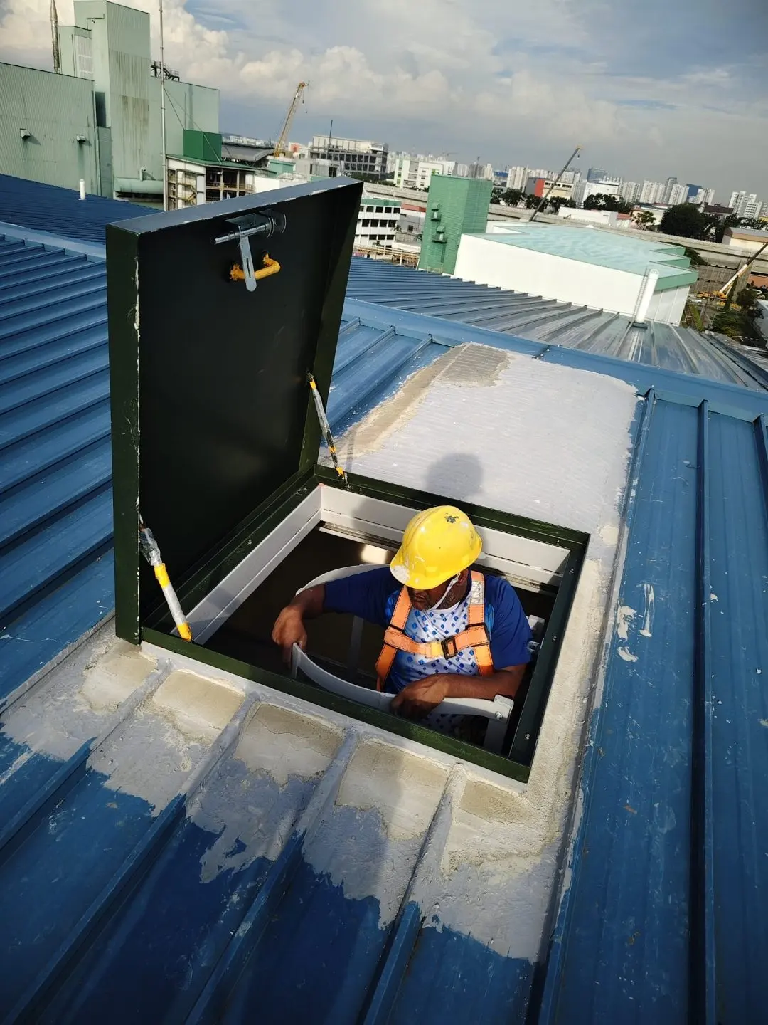 Open roof access hatch on the metal-deck roof at Wan Lee with the cat ladder visible inside the opening